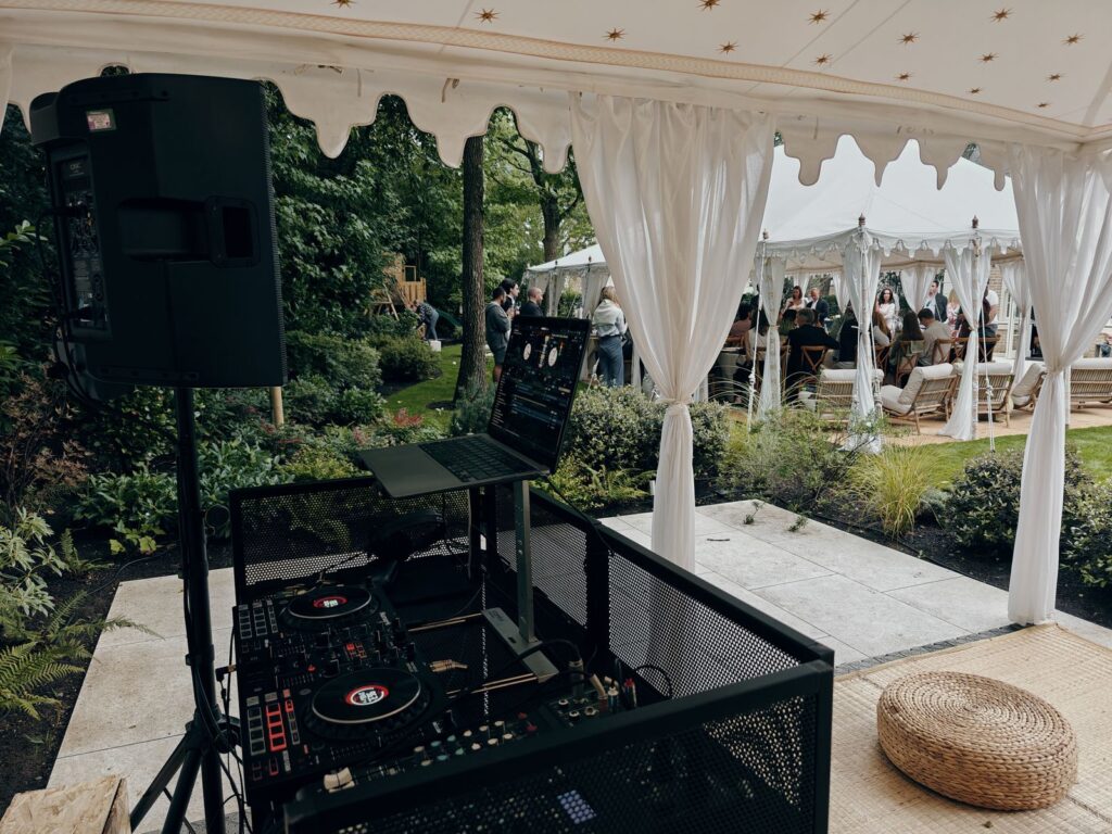 DJ controller, laptop stand and speaker under a garden marquee at a private party