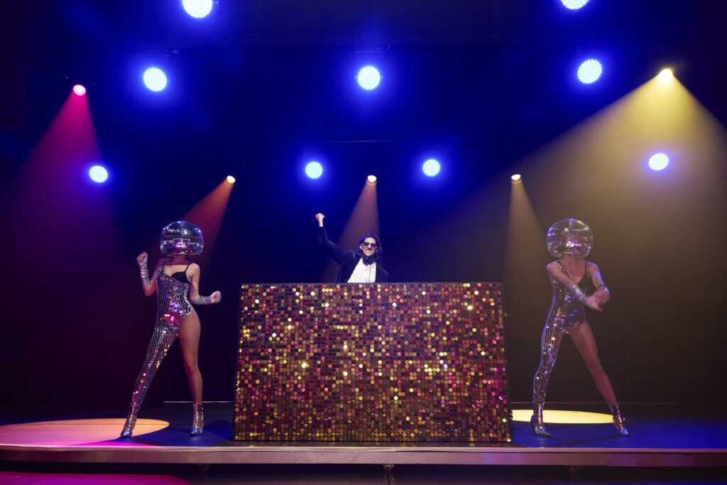 Corporate event DJ Monaco: DJ SR with his hands in the air between two disco ball dancers at Jimmyz, Monte-Carlo