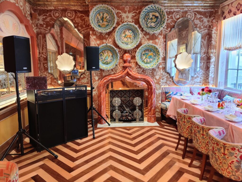 DJ booth and two speakers on stands set up beside the dining table in a private restaurant room