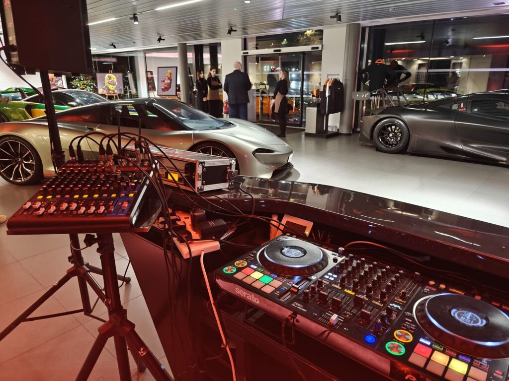 DJ controller, mixer and speaker on a stand at an evening launch event in a car showroom