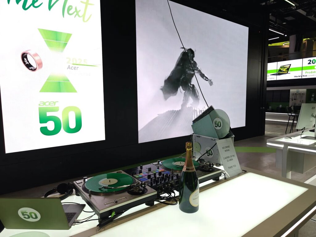 Technics turntables and a DJ mixer on a lit table in front of a large screen at a corporate event